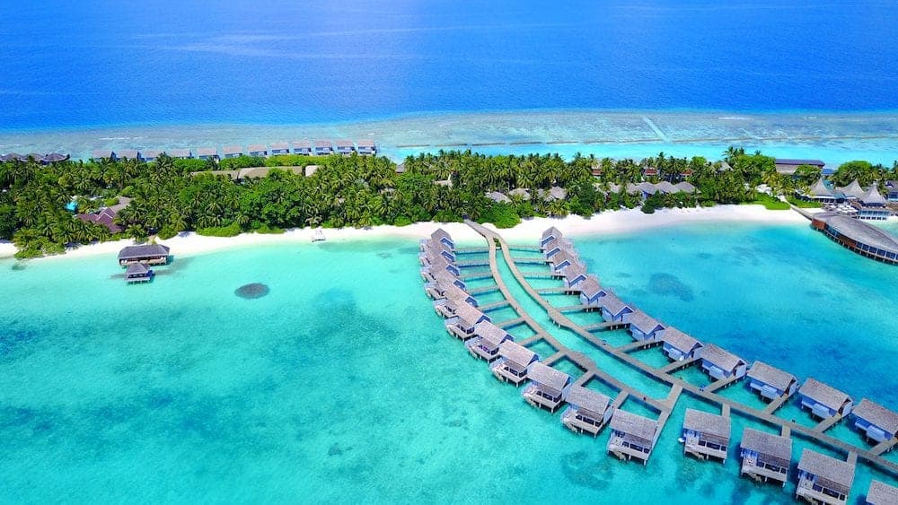 Aerial flying drone view of Maldives white sandy beach luxury 5 star resort hotel water bungalows relaxing holiday vacation on sunny tropical paradise island with aqua blue sky sea ocean 4k.