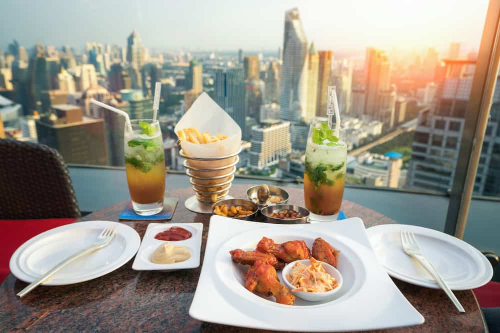 Food, snacks and mojito cocktail on the deak in rooftop bar in Bangkok city, Thailand