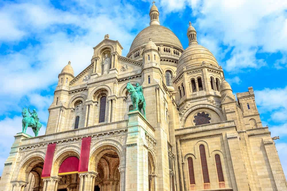 Bottom view of facade of Sacred Heart of Paris church in France. Basilique du Sacre-Coeur de Montmartre, the historic district of Paris Capital. Popular tourist landmark in a Capital of France.