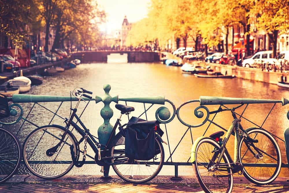 Bikes on the bridge in Amsterdam Netherlands Europe. Amsterdam canal scene with bicycles and bridges. Photo toning at retro color. Spring or autumn time in the city. Travel Europe.