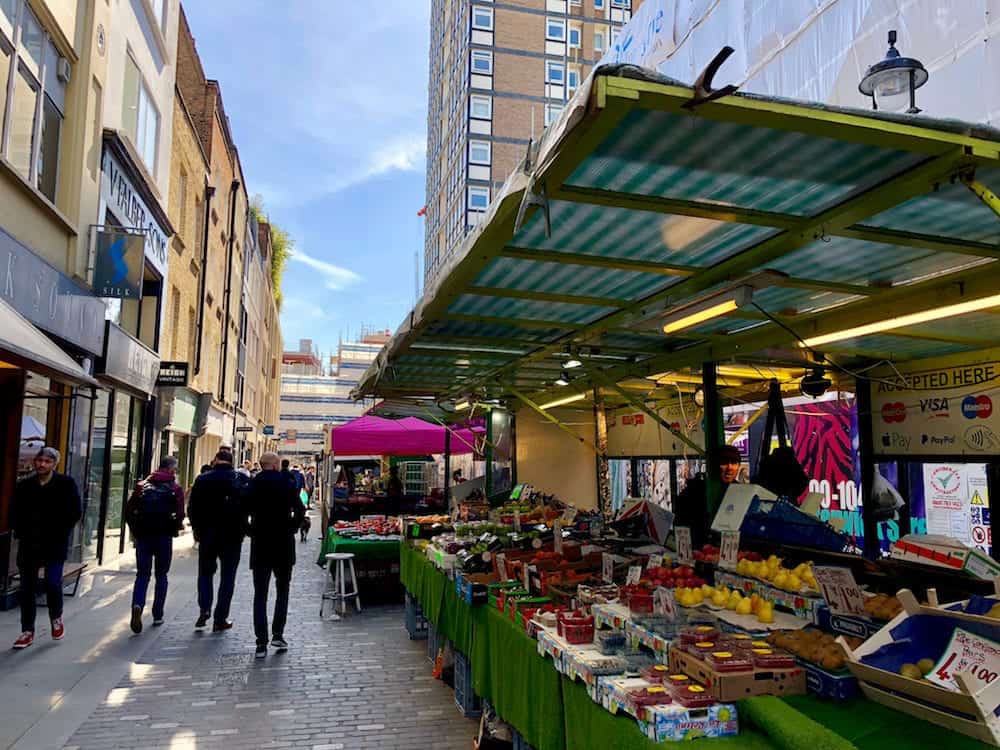 SOHO, LONDON -: Pedestrians at a market selling food, flowers, fruit and vegetables on Berwick Street in Soho, London, UK.