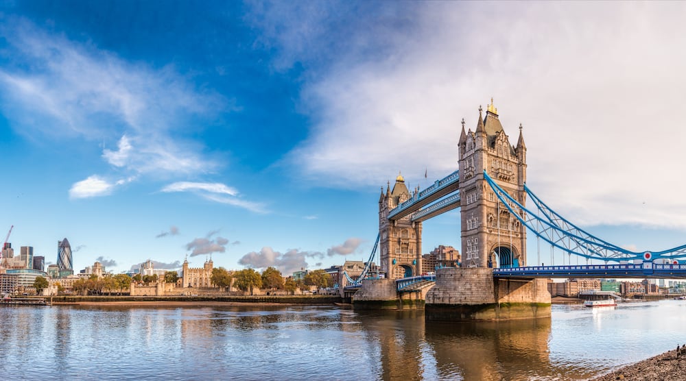 Panoramic London skyline with iconic symbol, the Tower Bridge and Her Majesty's Royal Palace and Fortress, known as the Tower of London as viewed from South Bank of River Thames in the morning light