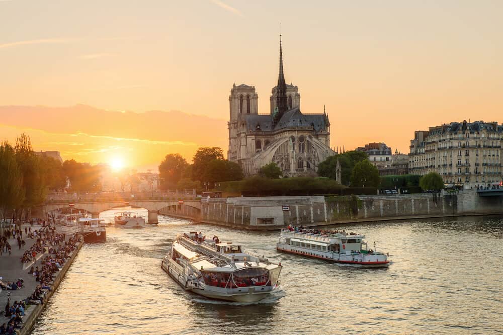 Notre Dame de Paris cathedral with cruise ship in Seine river in Paris France. Beautiful sunset in Paris France