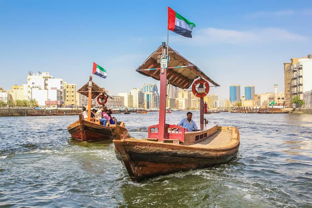 Dubai, United Arab Emirates -Traditional Abra ferries along Dubai Creek. The Creek divides the city into two main sections: Deira and Bur Dubai. On background, Twin Towers, old downtown.