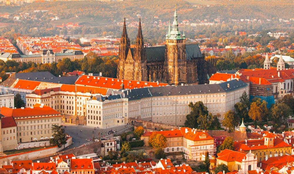 Prague Castle complex with gothic St Vitus Cathedral in the evening time illuminated by sunset, Hradcany, Prague, Czech Republic. UNESCO World Heritage. Panoramic aerial shot from Petrin Tower.