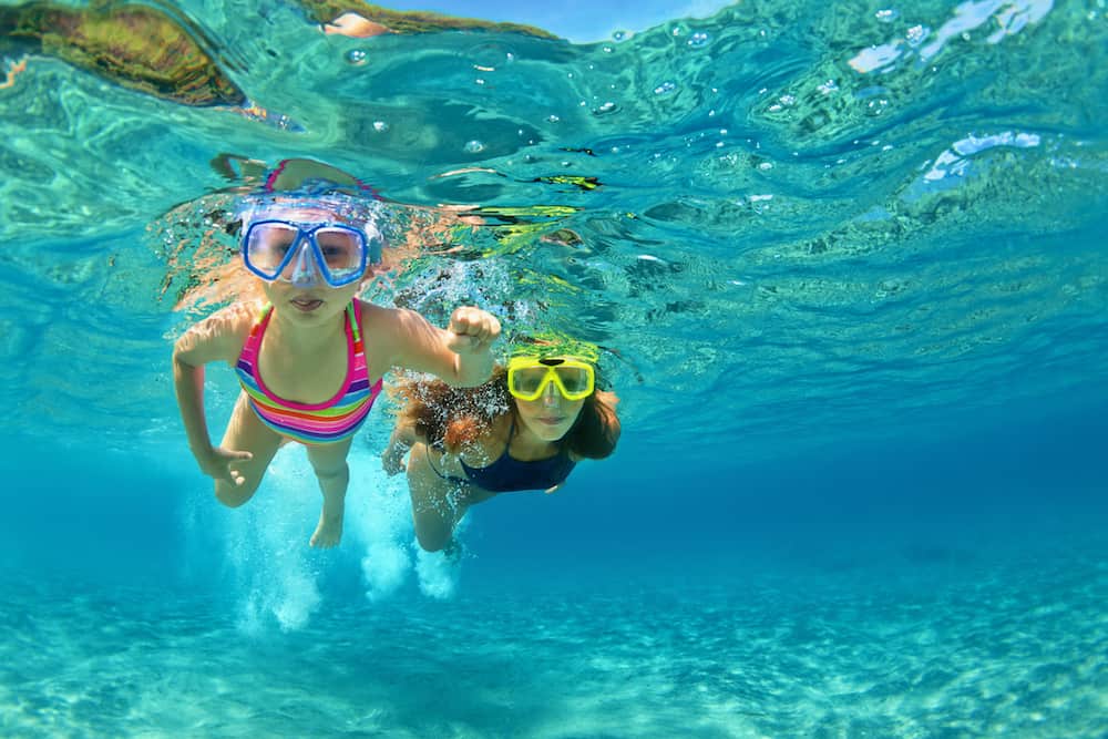 Happy family - mother with baby girl dive underwater with fun in sea pool. Healthy lifestyle active parent people water sport outdoor adventure swimming lessons on beach summer holidays with child