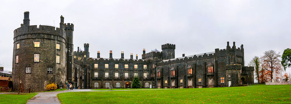 Kilkenny Castle during the day. It is one of the most visited tourist sites in Kilkenny Ireland. Castle grounds with green lawn and flowers. Landmark in small town of Ireland