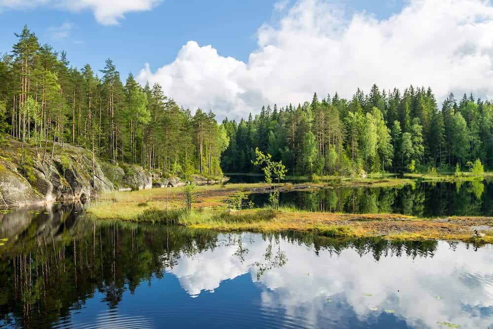 White summer clouds reflecting on the forest pond in Nuuksio National Park in Southern Finland
