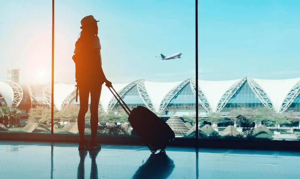Silhouette woman travel with luggage looking without window at airport terminal international or girl teenager traveling in vacation summer relaxation holding suitcase and backpack