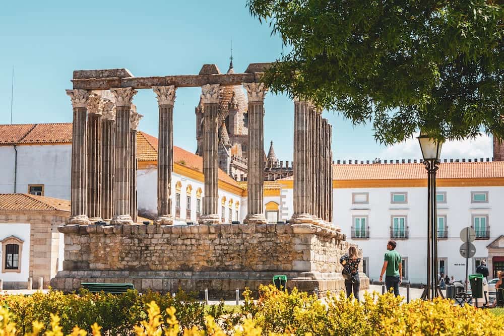 Evora, Portugal - architectural detail of the Roman temple of Evora in Portugal or Temple of Diana in front of which people are walking on a spring day. It is a UNESCO World Heritage Site