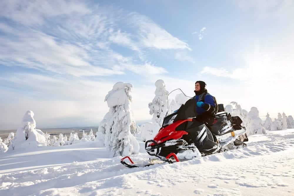Man driving snowmobile in snowyfield in a sunny day. Lapland, Finland.