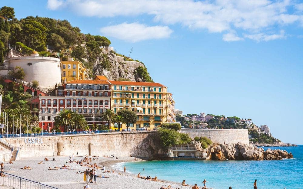 NICE, FRANCE -Beautiful nicoise architecture and people relaxing on beach that stretches along Promenade des Anglais in Nice