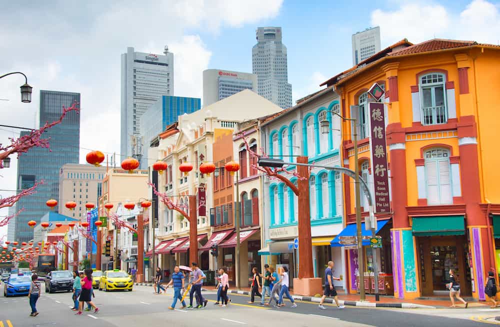 SINGAPORE - People crossing the road in Chinatown of Singapore. Modern skyscrapers of Singapore Downtown on a background.