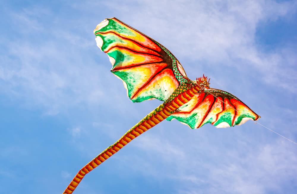 Indonesian kite with an ugly dragon head and a long tail flying in the wind, Sanur, Bali, Indonesia