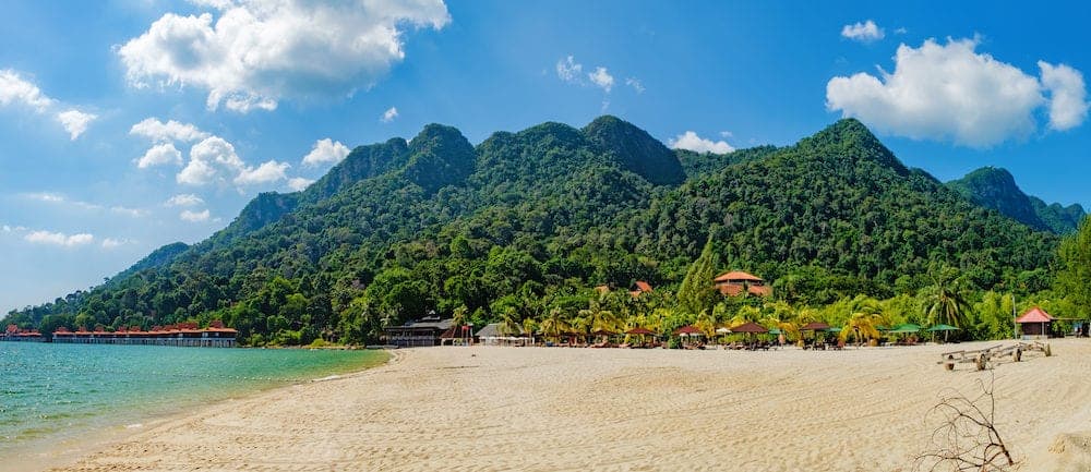 Relaxing on remote paradise beach. Tropical bungalow and luxury house on untouched sandy beach with palms trees in Langkawi Island, Malaysia.