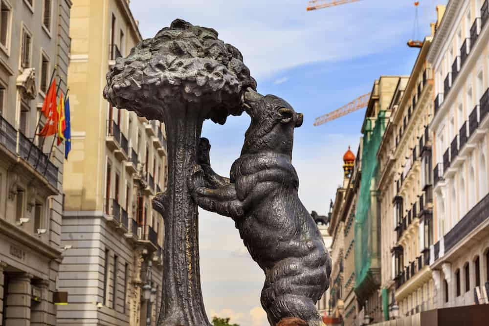 MADRID, SPAIN - Bear and Mulberry Tree El Oso y El Madrono Statue Symbol of Madrid Puerta del Sol Gate of the Sun Most Famous Square Building Cranes in Madrid Spain Statue created in 1967 by sculptor Antonio Navarro Santa Fe