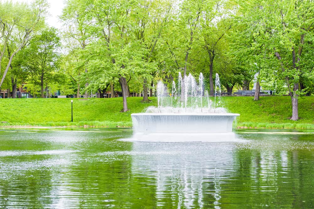 Montreal Canada - Green fountain and lake in La Fontaine Park in Quebec region city during summer