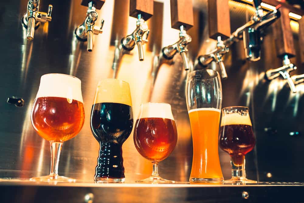 The beer taps in a pub. nobody. Selective focus. Alcohol concept. Vintage style. Beer craft. Bar table. Steel taps. Shiny taps. Glass of beer