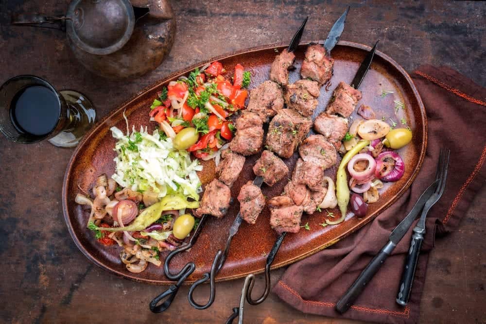 Traditional Turkish lamb kebab barbecue skewer with cabbage and tomato onion salad as top view on a plate