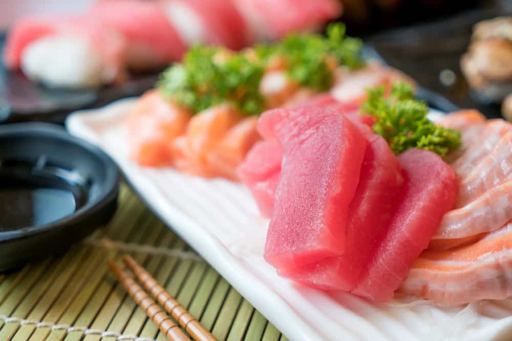 Mixed sliced fish sashimi in white plate. Sashimi Salmon and Tuna set with Tuna, flying fish roe caviar and Foie Gras closeup. Japan restaurant menu