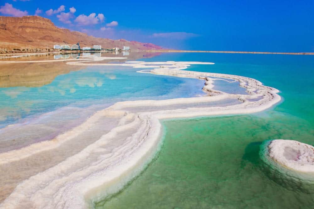 The concept of ecological and medical tourism. Very salty water glows with turquoise light. Reduced water in the Dead Sea, Israel