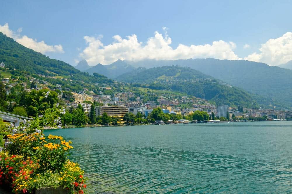 View to Montreux city from Geneva lake embankment at sunny summer day, flowers at foreground.