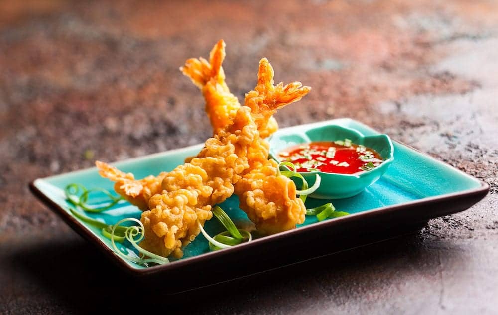 Shrimps tempura with spicy chili sauce on blue plate. Seafood tempura dish of traditional asian cuisine .