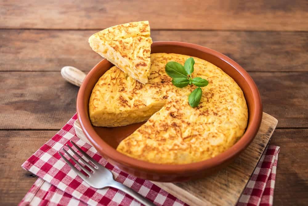 Spanish potato omelet called tortilla de patatas on a rustic wooden texture with a place for text