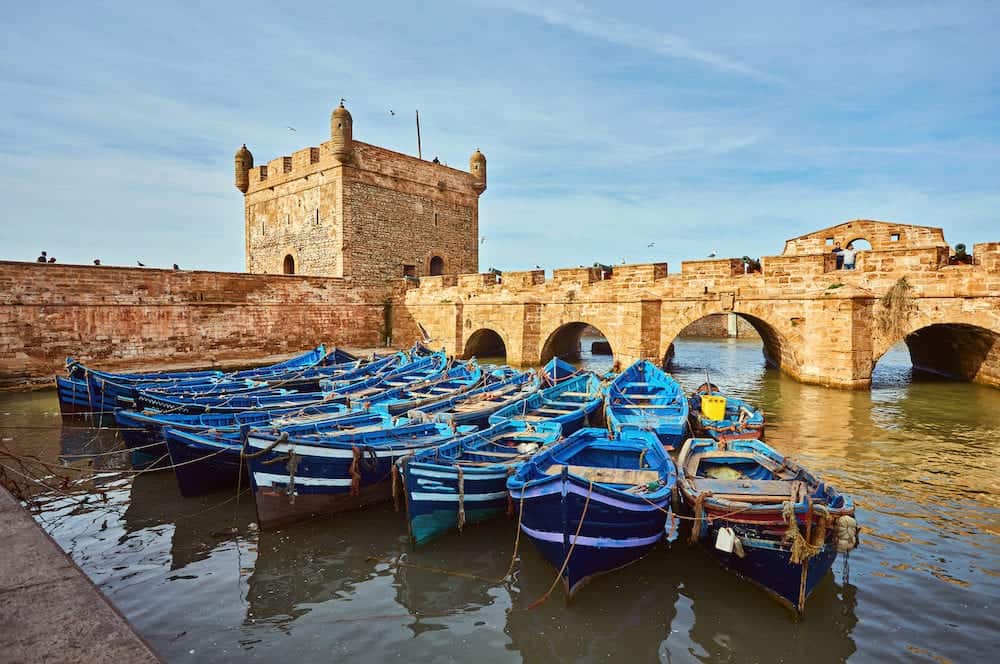 Fort of Essaouira in Morocco on a sunny day with blue boats on the water and selective focus