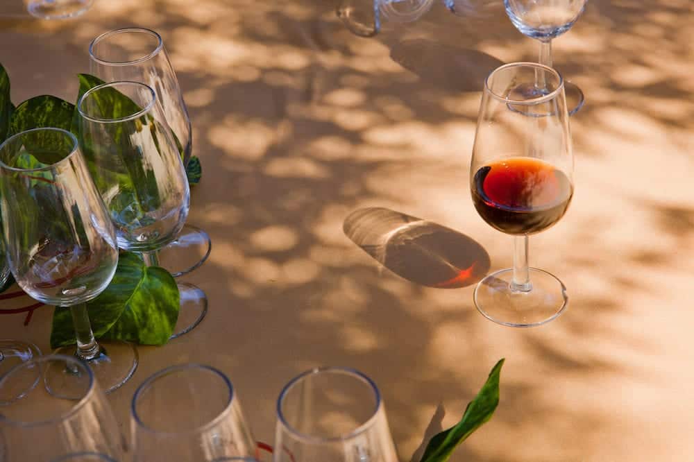 Glass full of sherry on a wooden table with other empty cups and vegetal decoration