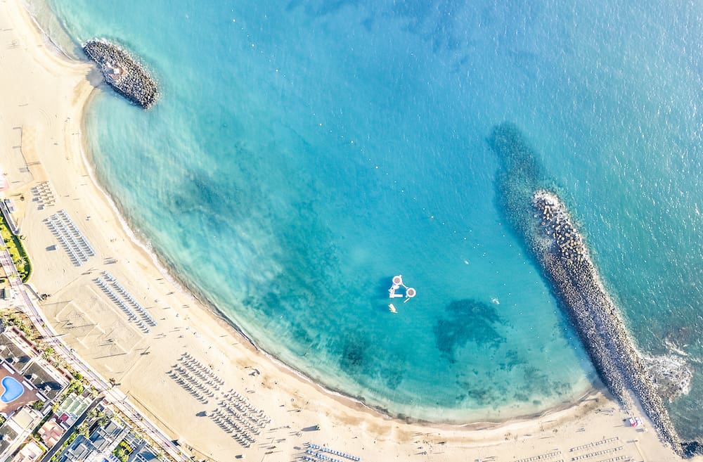 Aerial view of Los Cristianos bay beach in Tenerife with sunbeds and umbrellas miniature - Travel concept with nature wonder landscape in Canary islands Spain - Bright warm day filter