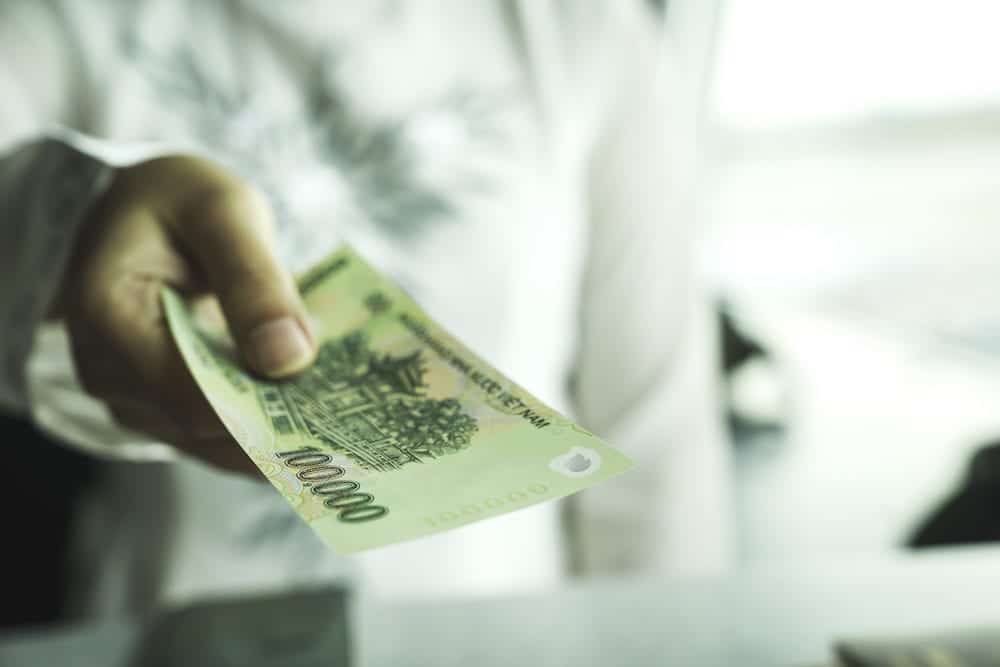 Close up of asian woman's hand holding vietnam bank note make payment at shop or supermarket. Asia currency exchange or finance concept. Vietnamese giving money or opportunity support in investment.
