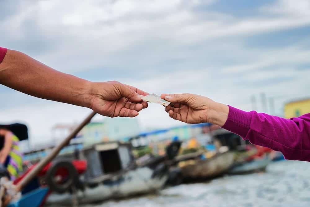 The moment of purchase and exchange of money for the goods at the Floating market at the delta Mekong in Can Tho, Vietnam