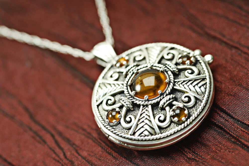 Celtic Siver And Amber Locket on red silk.