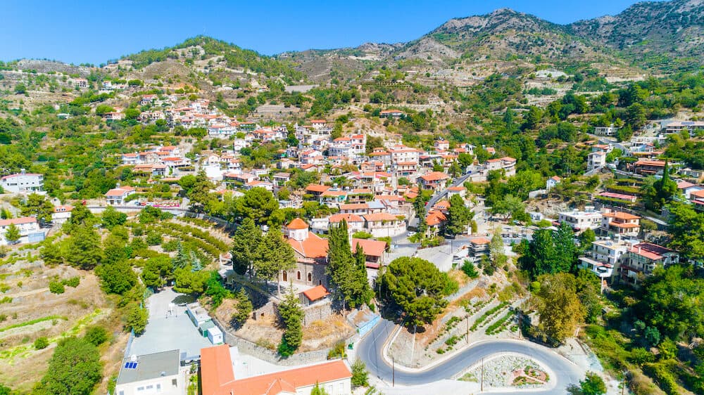 Aerial view of Agros village settlement on mountain Troodos, Limassol district, Cyprus. Bird's eye view of traditional houses with ceramic tile roof, church, countryside and rural landscape from above.