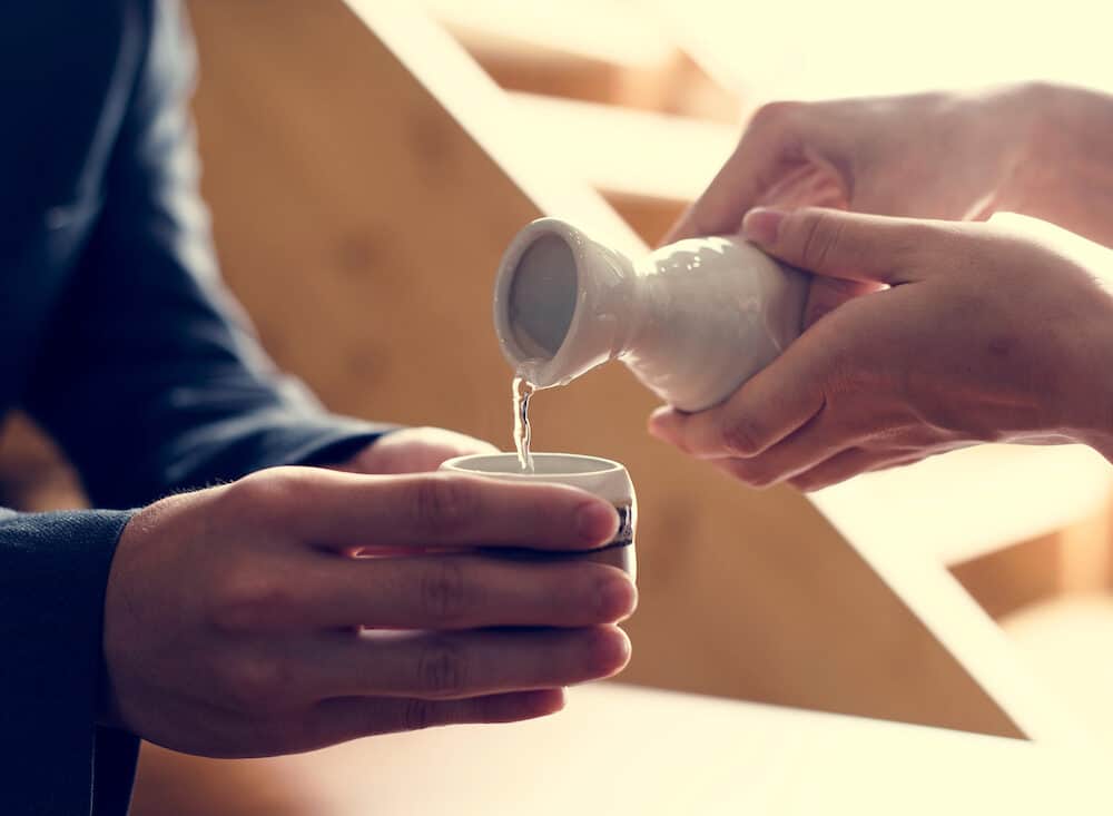 Sake Pouring From A Bottle Into A Cup
