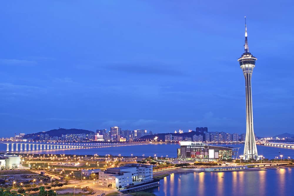 Urban landscape of Macau with famous traveling tower under sky near river in Macao Asia.