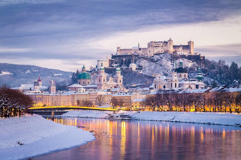 Classic view of the historic city of Salzburg with famous Festung Hohensalzburg and Salzach river illuminated in beautiful twilight during scenic Christmas time in winter Salzburger Land Austria