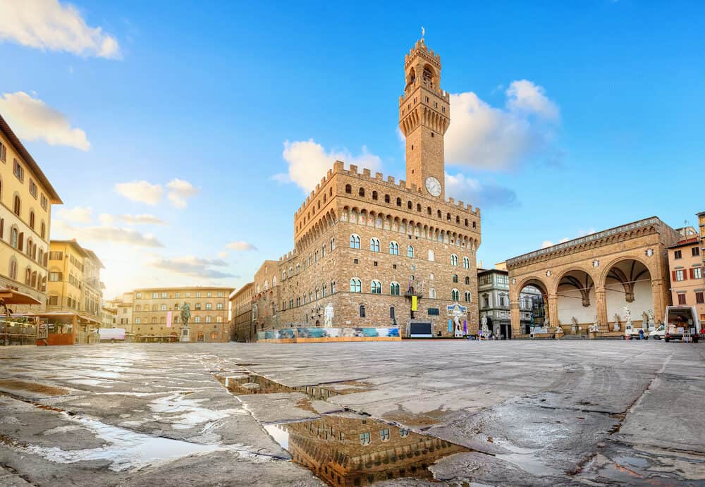 Florence, Italy. View of Piazza della Signoria square with Palazzo Vecchio reflecting in a puddle at sunrise