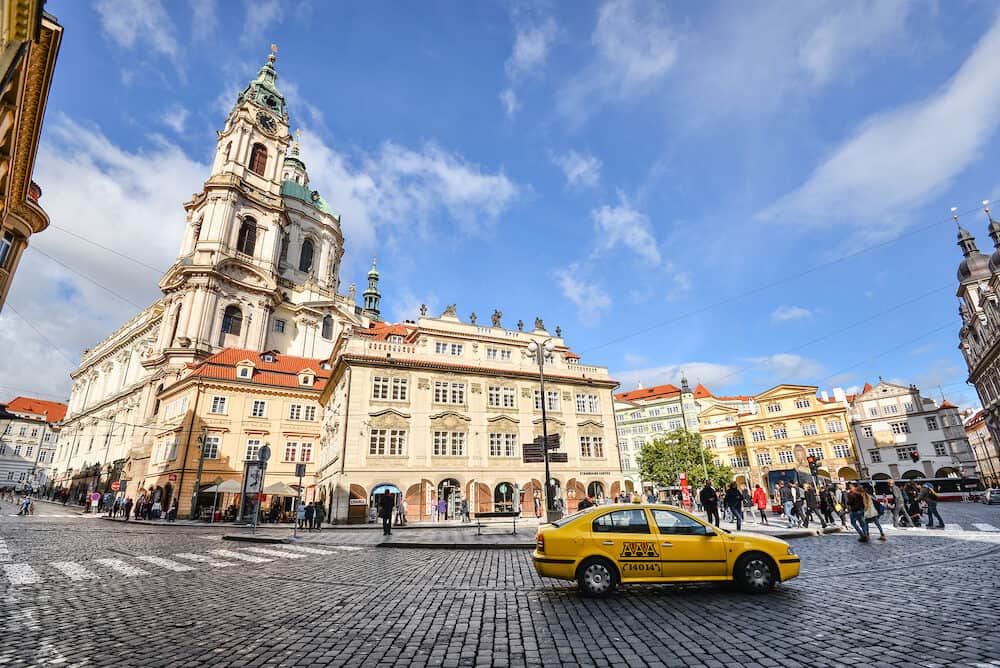 Prague, Czech Republic - Yellow taxi cab and ancient Church of Saint Nicholas in the Lesser Town of Prague, Czech Republic