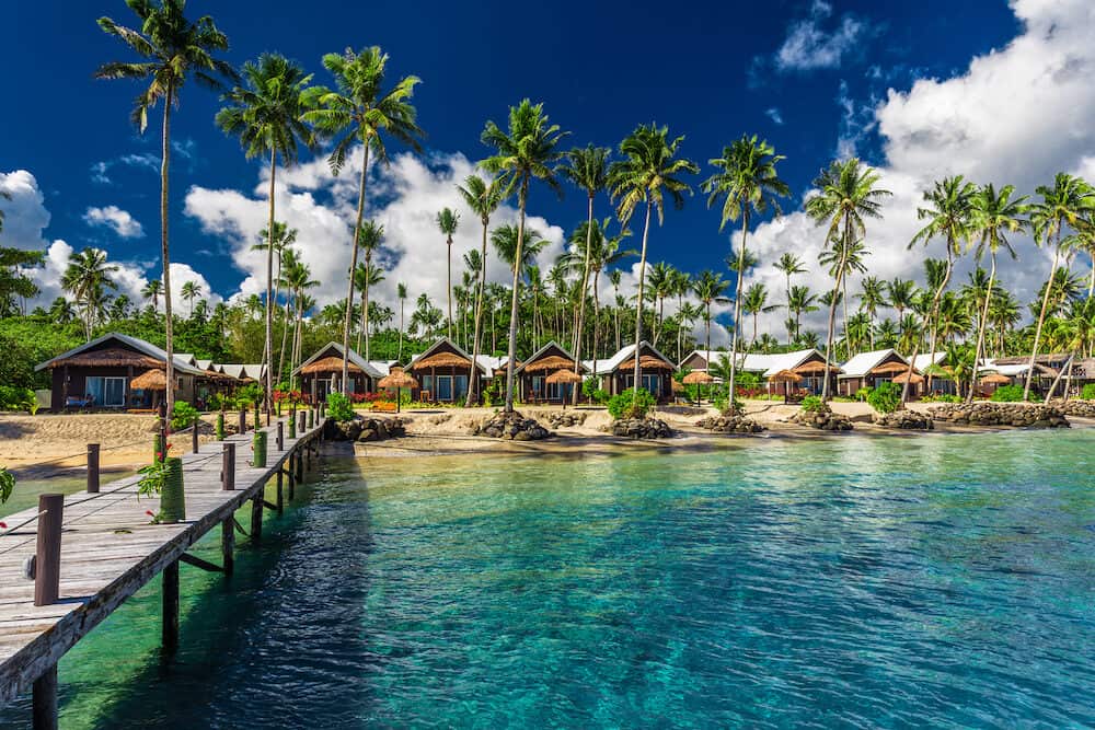 Amazing tropical beach with with coconut palm trees and villas on Samoa Island