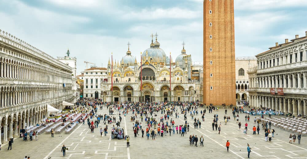 Venice, Italy - Piazza San Marco or St Mark`s Square in Venice. It is a top tourist attraction of Venice. Panoramic view of the famous Venice center in summer. People walk near Basilica.