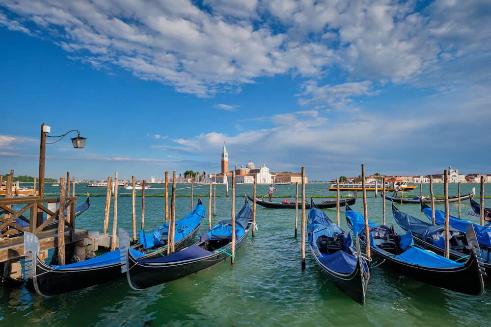 VENICE, ITALY - Gondolas and gondolier in lagoon of Venice by Saint Mark (San Marco) square with San Giorgio di Maggiore church in background in Venice, Italy