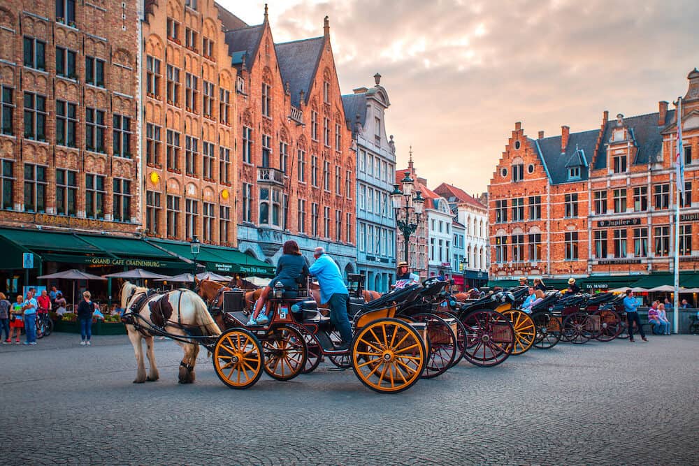 Bruges, Belgium - Market Square in Bruges with tourists. Vintage horse carriage entertainment for tourists in Bruges.