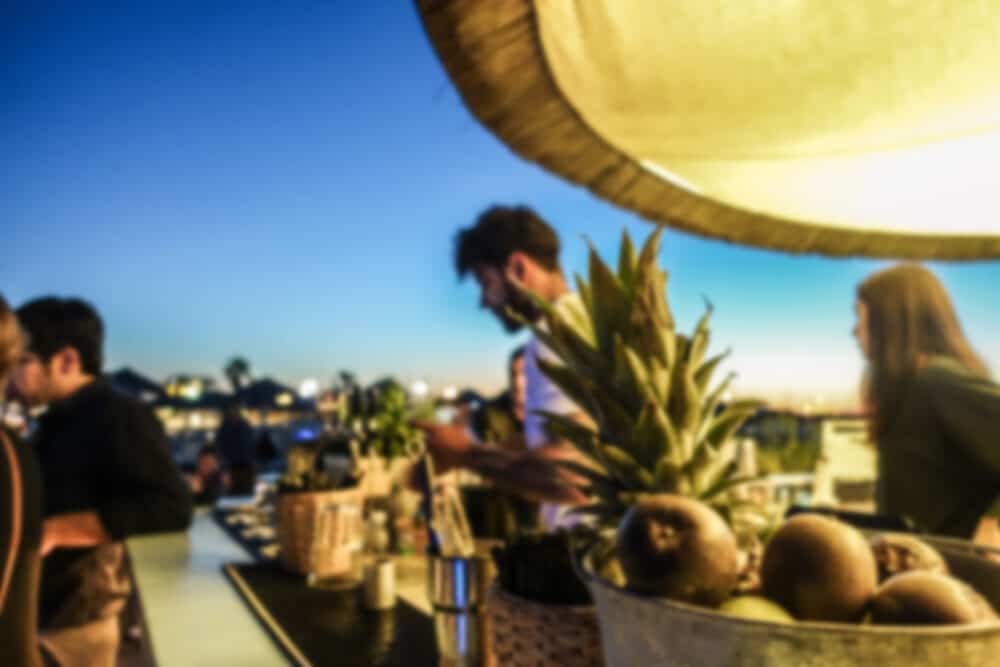 Blurred barman working in chiringuito bar at sunset beach party - Concept of nightlife with cocktails and music entertainment in summer vacation