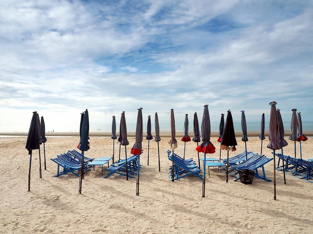 Colorful beach chairs and umbrellas with blue sky for tourism relax in vocation at Cha-Am beach Thailand
