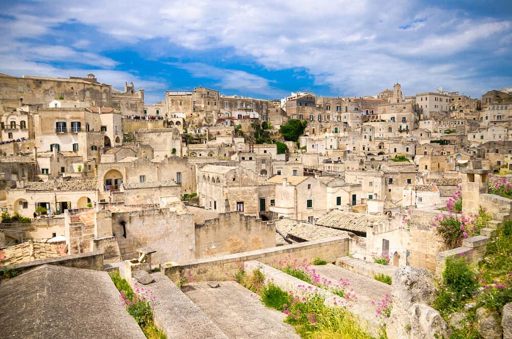 Sassi di Matera panoramic view of historical centre Sasso Caveoso of old ancient town with rock cave houses in front of blue sky and white clouds, UNESCO World Heritage, Basilicata, Southern Italy