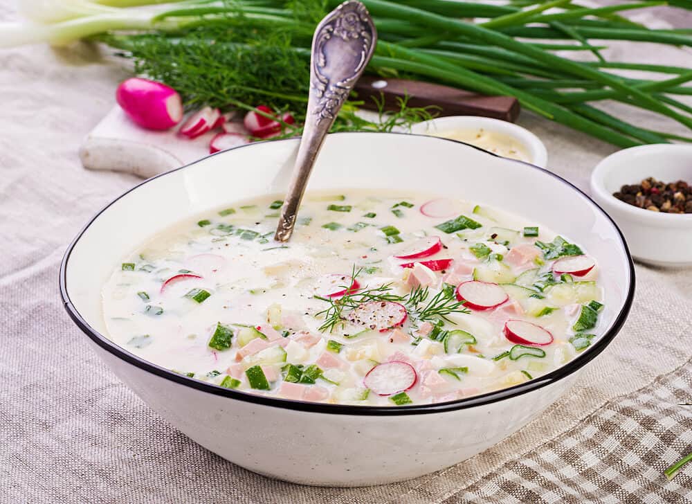 Cold soup with fresh cucumbers, radishes, potato and sausage with yoghurt in bowl. Traditional russian food - okroshka. Summer cold soup.