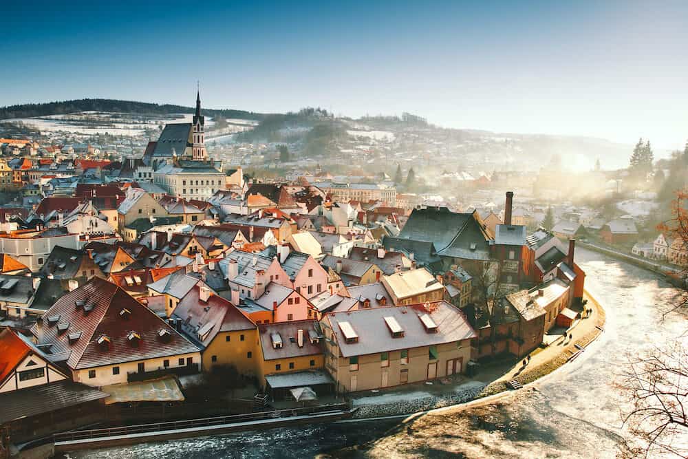 Panoramic view of Cesky Krumlov in winter, Czech Republic. View of the snow-covered red roofs. Travel and Holiday in Europe. Christmas and New Year time. Sunny winter day in european town.