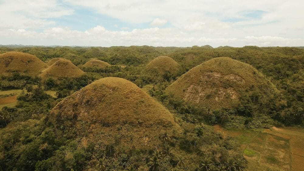 Amazingly shaped Chocolate hills on sunny day on Bohol island, Philippines. Aerial view Chocolate Hills in Bohol, Philippines are earth mounds scattered all over the town of Carmen. Travel concept.